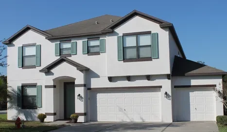 Two-story Lakeland home painted in warm white with sage green shutters by Mike's Painting